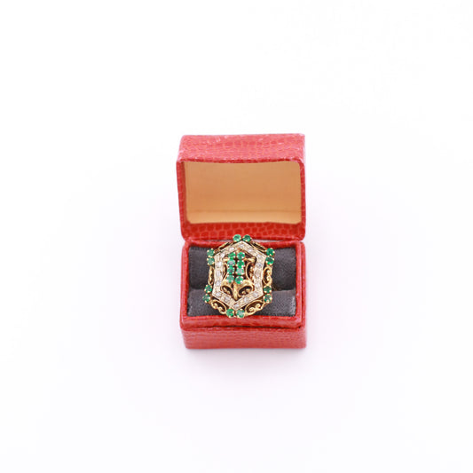 Decorative ring with emerald gemstones in a red jewelry box on a white background