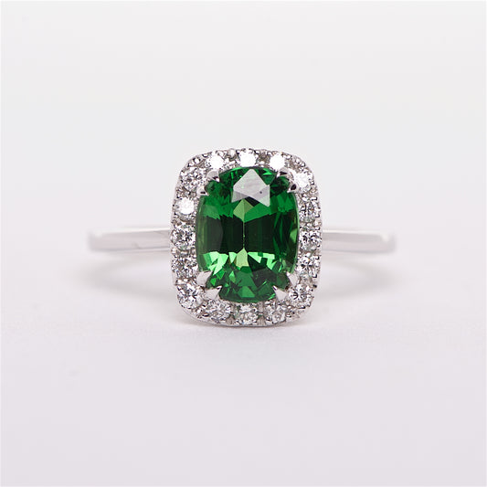 An 18K white gold ring featuring a vibrant green rare tsavorite gemstone centerpiece surrounded by round brilliant diamonds.