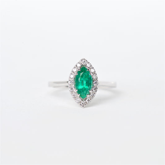An 18K white gold ring featuring a marquise-shaped Colombian emerald centerpiece with surrounding round brilliant diamonds.