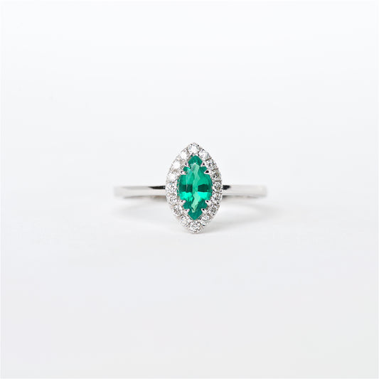 An 18K white gold ring featuring a central Colombian emerald gemstone, surrounded by round brilliant cut diamonds set in a halo design.