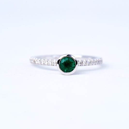 A 14K white gold emerald and diamond ring with the main emerald stone set in a white gold band, surrounded by smaller round brilliant diamonds.